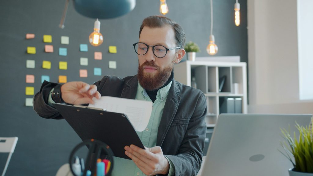 Man in glasses reviewing documents at desk.